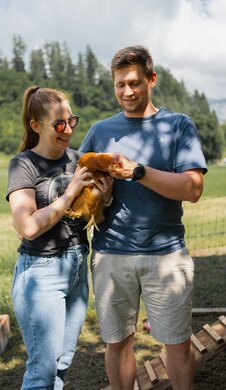 Viktoria und Klement halten ein Huhn in den Händen.
